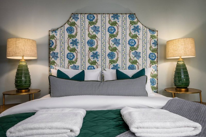 Bedroom with upholstered headboard, white bedding, green accents, and matching table lamps