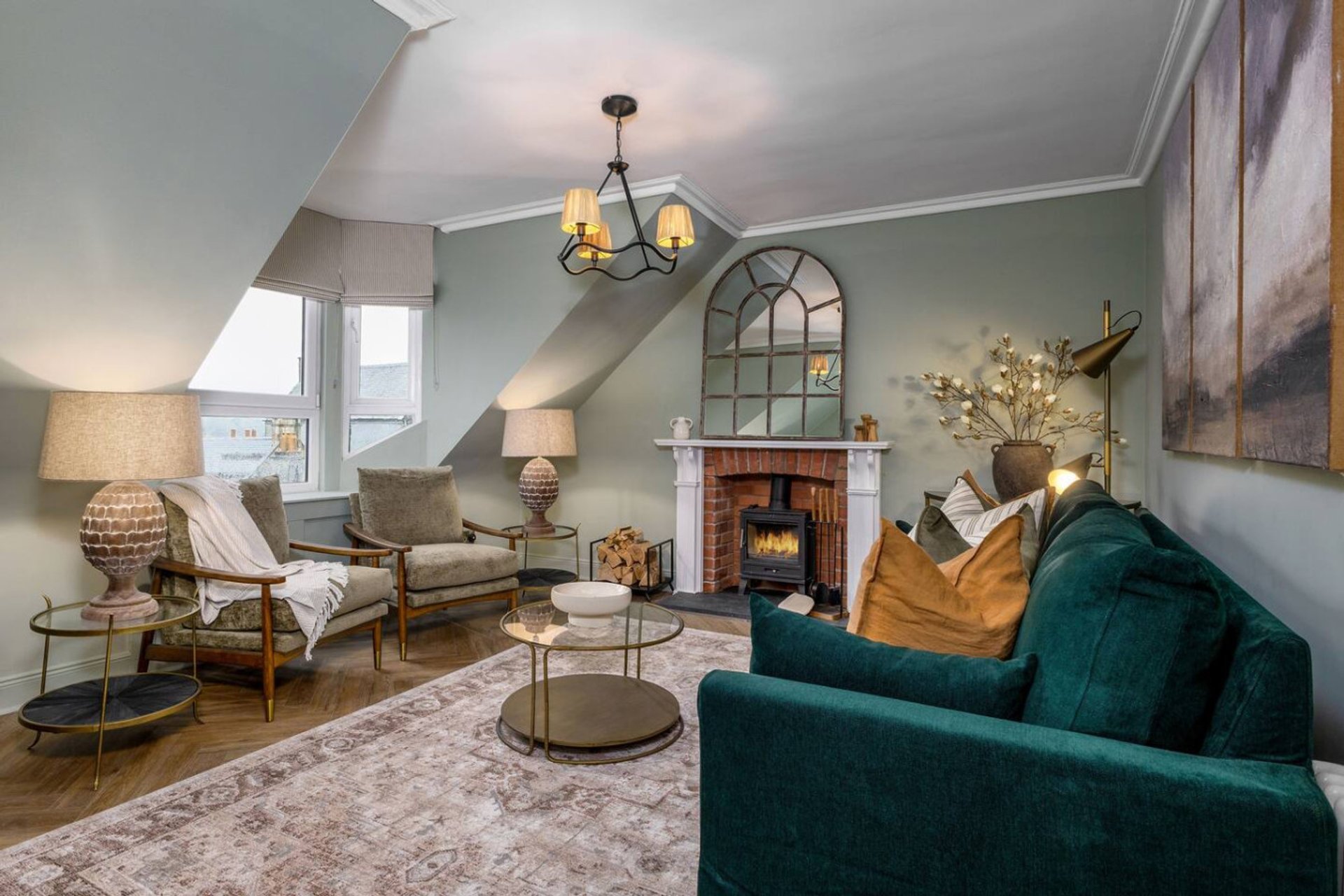Spacious living room with fireplace, vaulted ceiling, green sofa and armchairs