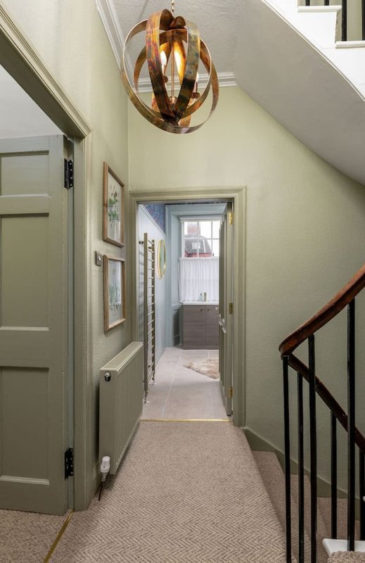 Hallway with pendant light, carpet flooring, staircase and framed wall art