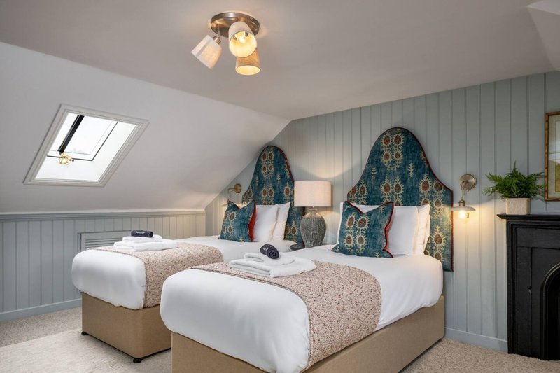 Attic bedroom with two single beds, decorative headboards, skylights and sloped ceilings