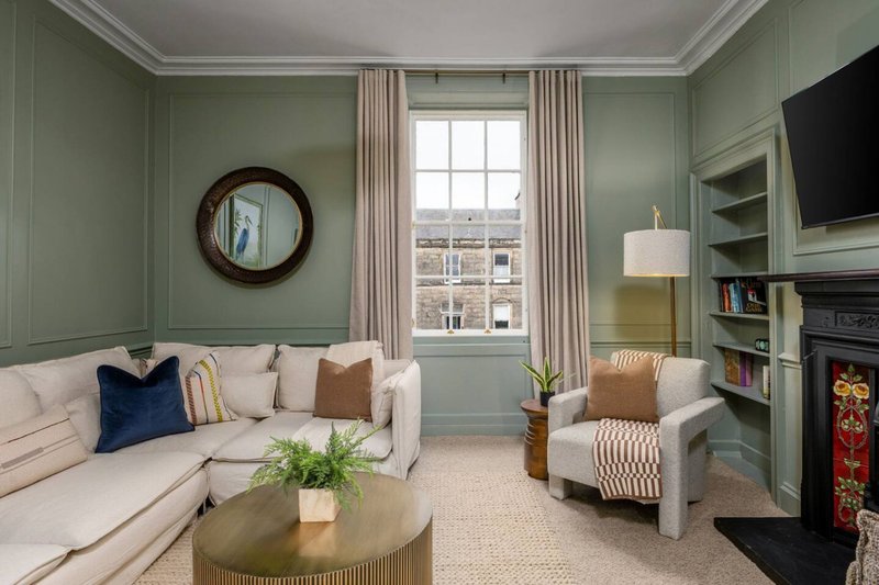 Elegant living room with cream sofa, armchair, round coffee table and fireplace