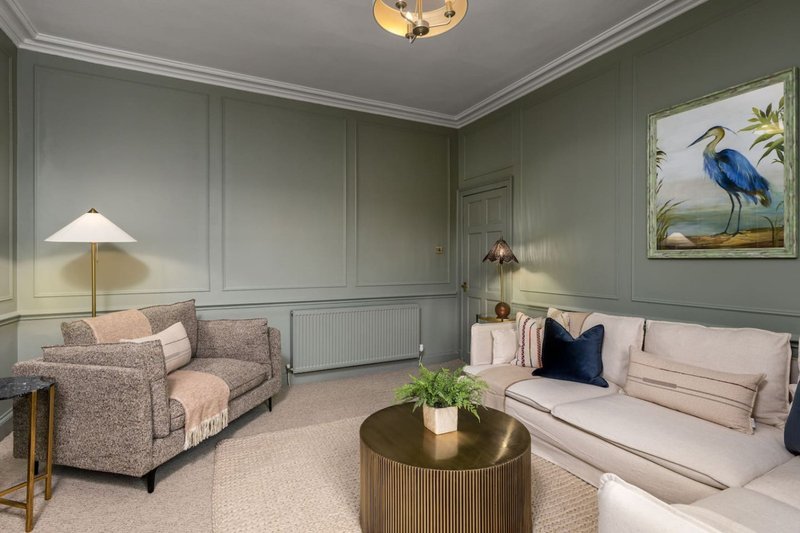 Elegant sitting room with patterned armchair, cream sofa, round table, and wall art
