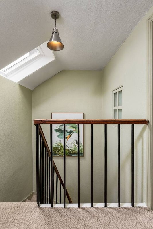 Bright loft space with skylight, wooden railing, pendant light and potted plant