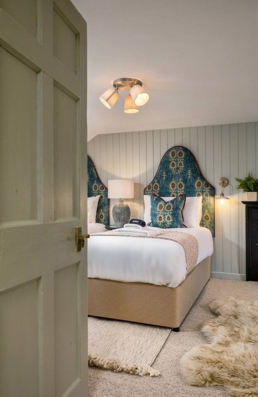 Bedroom with double bed, patterned headboard, white bedding, and ceiling light fixture