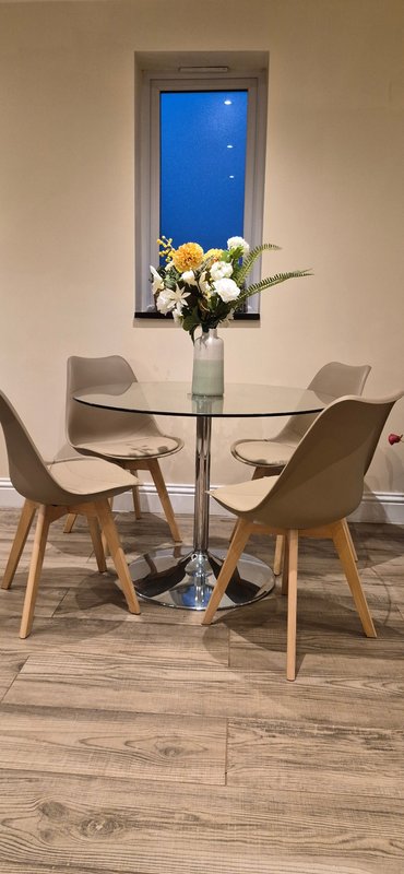 Dining area with small round table, two chairs, and yellow flowers in vase