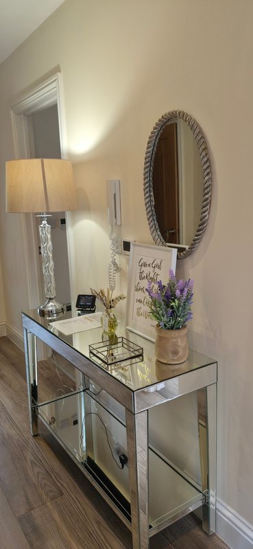 Hallway console table with mirror, lamp, flowers and decorative items