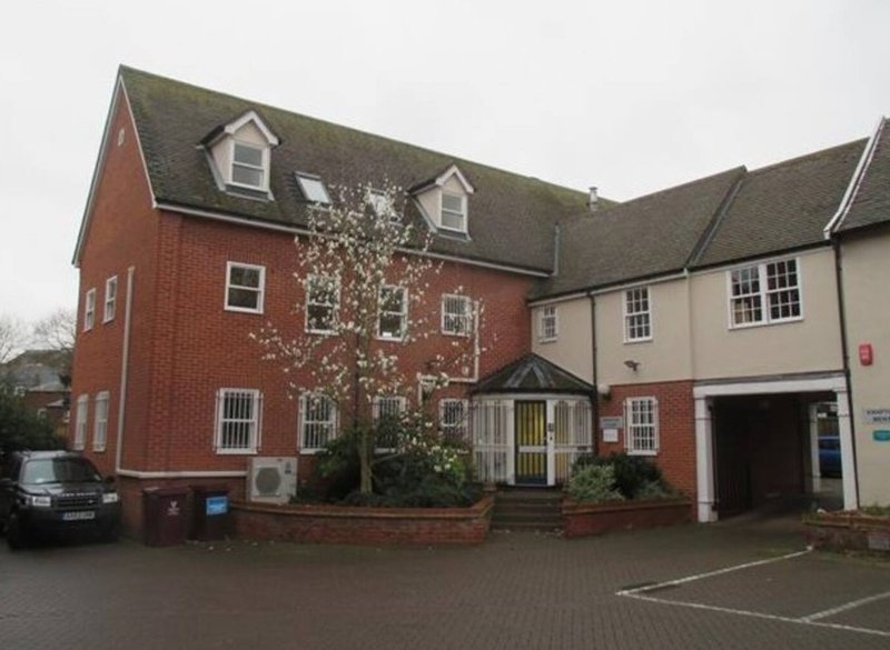 Two-storey brick residential building with driveway, parked car and front entrance