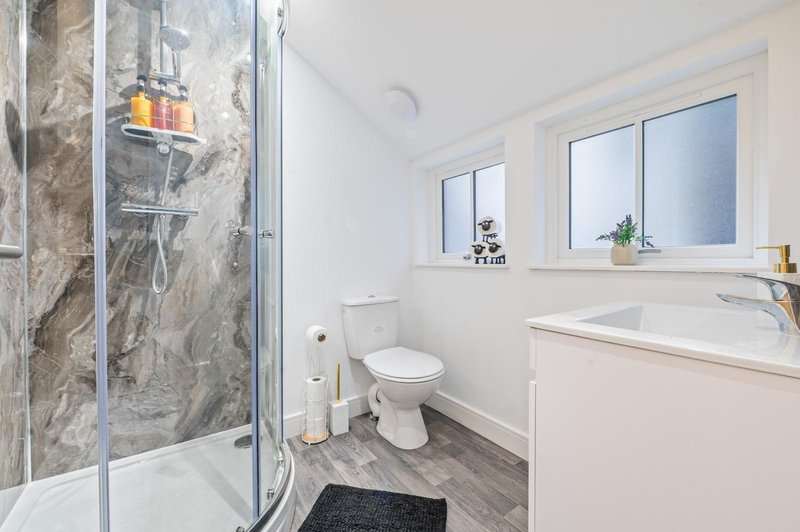 Modern bathroom with shower cubicle, toilet, vanity sink and windows