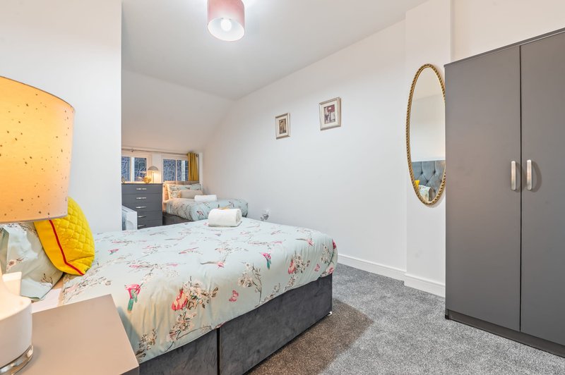 Bright bedroom with single bed, floral duvet, wardrobe, mirror and bedside lamp