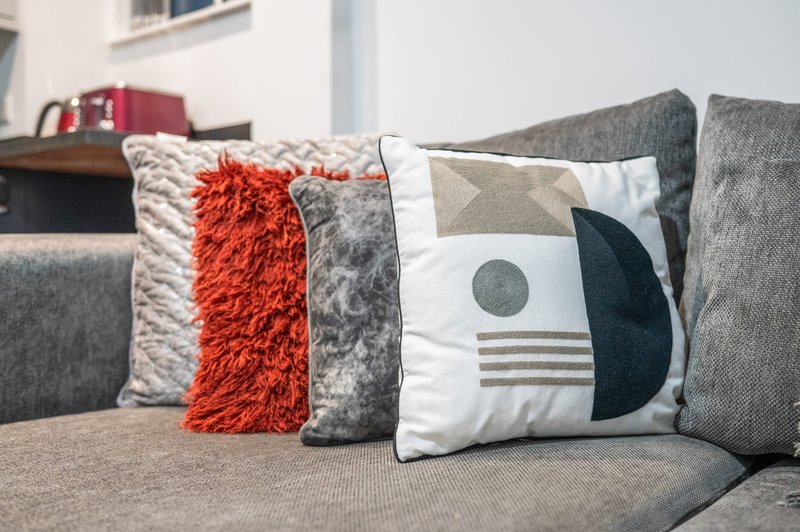 Gray sofa with decorative cushions in cream, orange, and patterned designs