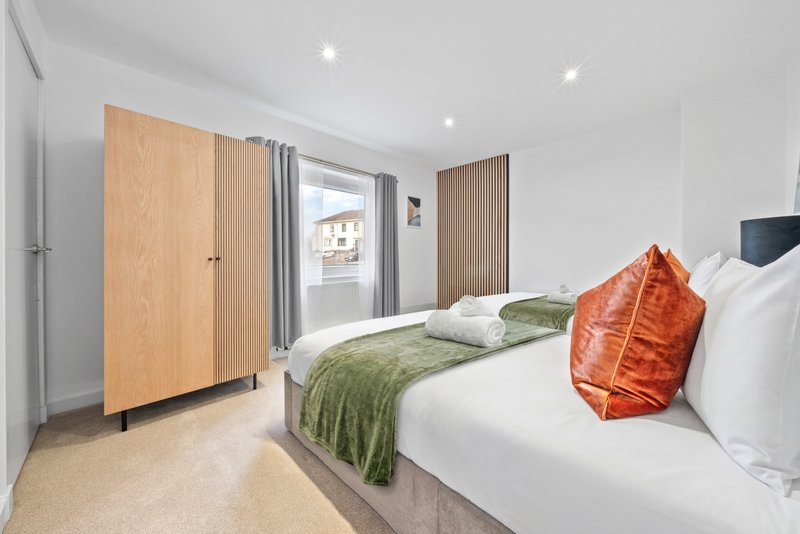 Modern bedroom with double bed, wooden wardrobes, and view to balcony door