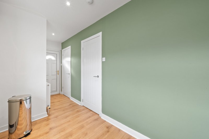Hallway with sage green walls, white doors, wooden flooring and stainless steel waste bin