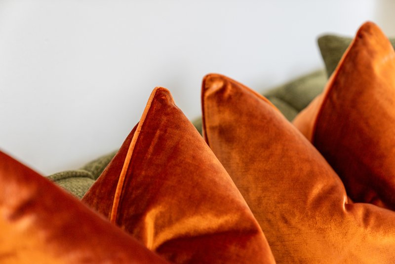 Close-up of orange and green velvet cushions or pillows with soft fabric texture