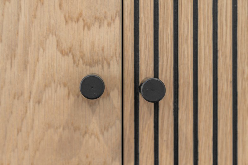 Close-up of wooden cabinet doors with black circular handles and metal trim details
