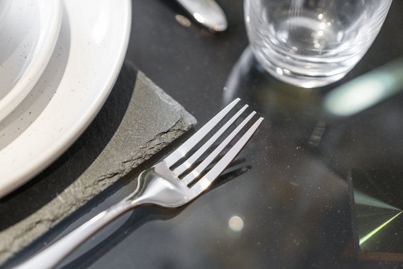 Table setting with fork, glass, and white plate on dark surface