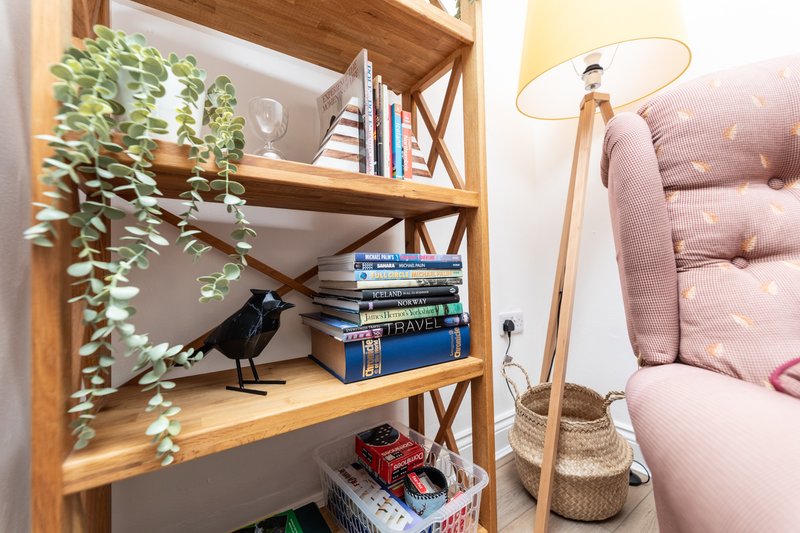 Wooden shelving unit with books, plants, decorative items and black bird figurine