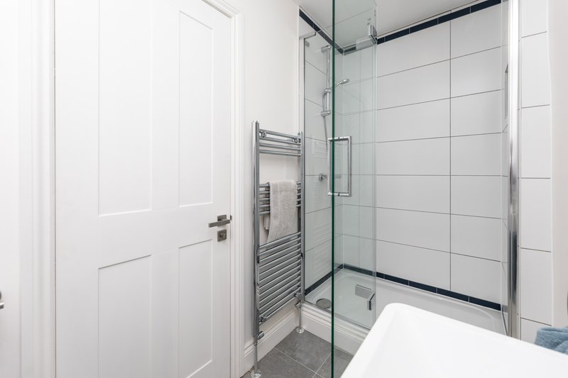 Modern bathroom with walk-in shower, heated towel rail, and white subway tile