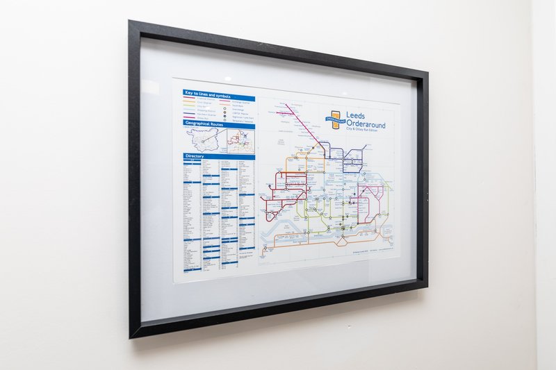 Framed wall display showing transit map and information charts in modern interior