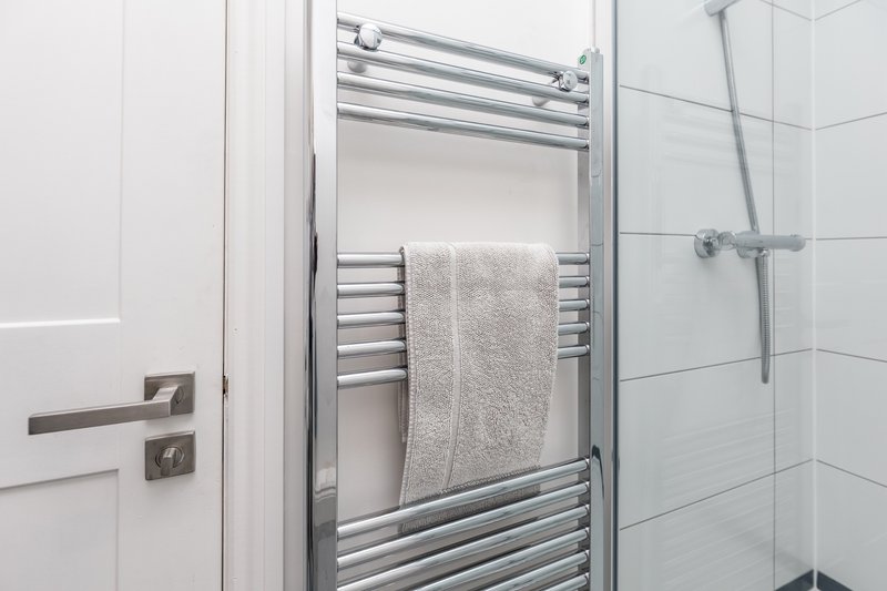 Modern bathroom with towel rail, shower enclosure and white tile walls