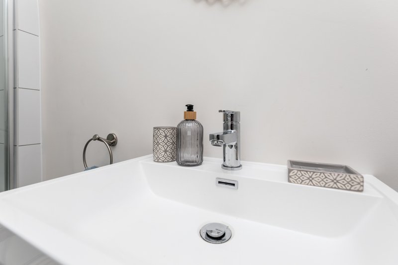 Modern white bathroom sink with chrome faucet, soap dispenser, and decorative accessories
