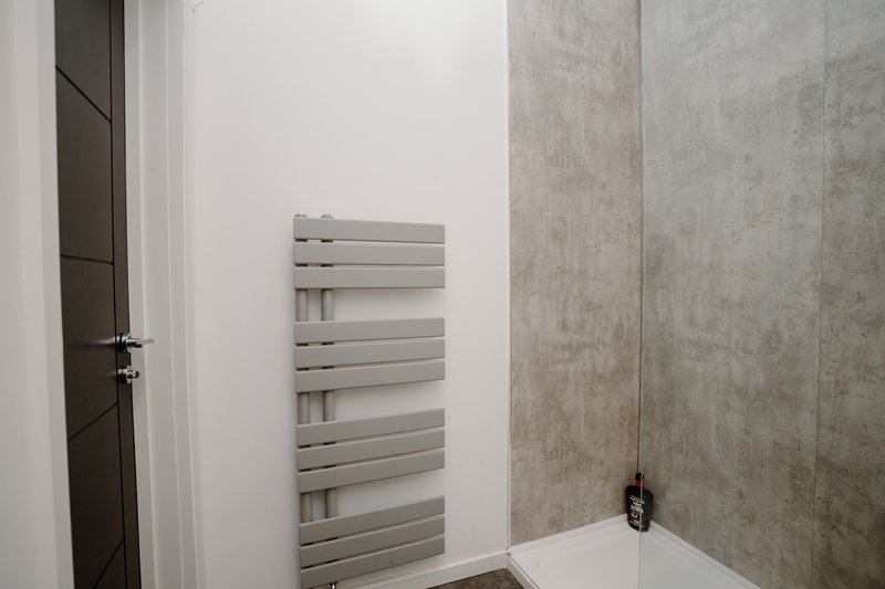 Modern bathroom with horizontal towel radiator, white wall and grey tile paneling