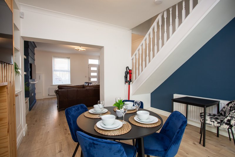 Open-plan dining and living area with round table, blue chairs, and staircase