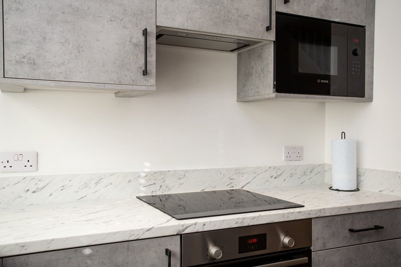 Modern kitchen with marble countertop, gray cabinets, built-in oven and cooktop