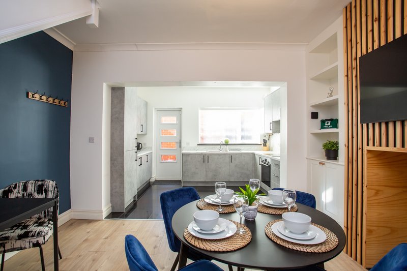Modern open-plan dining and kitchen space with blue feature wall and wooden slat paneling