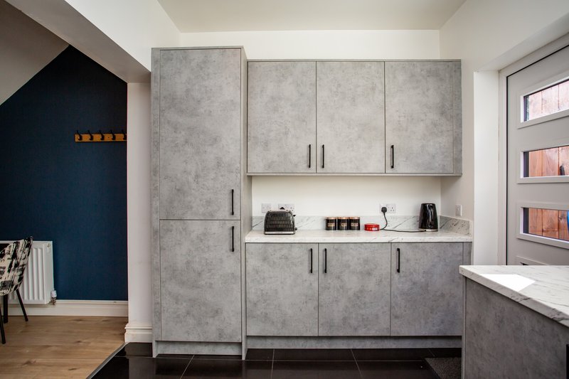 Modern kitchen with concrete-effect cabinetry, stainless steel handles, open shelving and appliances