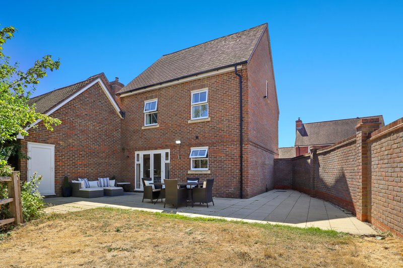 Brick detached house with patio, garden furniture, and fenced rear garden