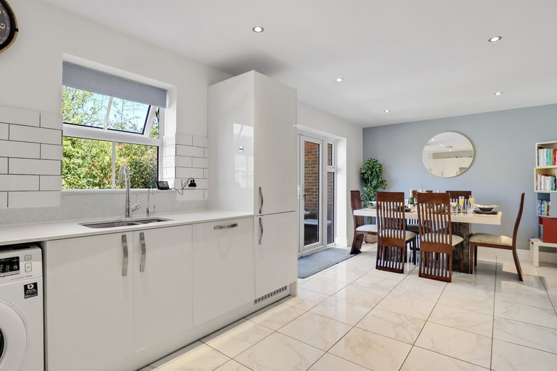 Open-plan kitchen and dining area with white cabinetry, dining table, and garden view