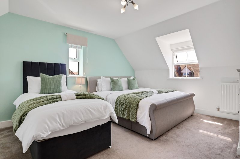 Bright attic bedroom with twin beds, mint green wall, white bedding and green accents
