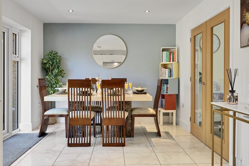 Modern dining area with wooden table, chairs, round mirror, and built-in shelving