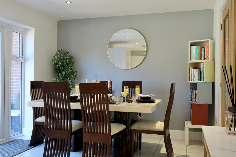 Bright dining room with dark wood table, six chairs, round mirror, and built-in bookshelf