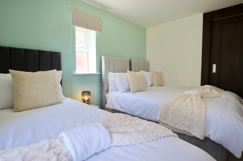 Twin bedroom with two single beds, mint green accent wall, cream pillows and white bedding