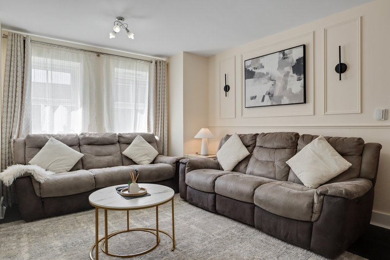 Modern living room with grey corner sofa, cream cushions, round coffee table and large windows