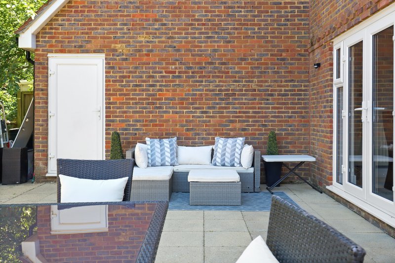 Brick patio with outdoor seating, garden furniture and white door access