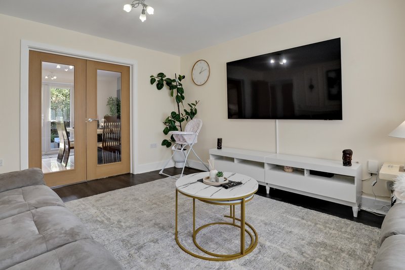Modern living room with gray sofa, wall-mounted TV, coffee table, and potted plants