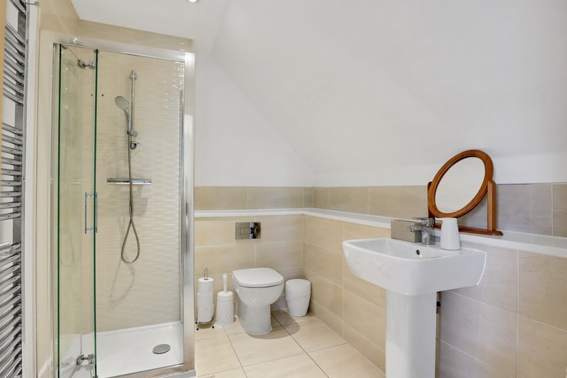 Modern bathroom with walk-in shower, white pedestal sink, toilet and heated towel rail