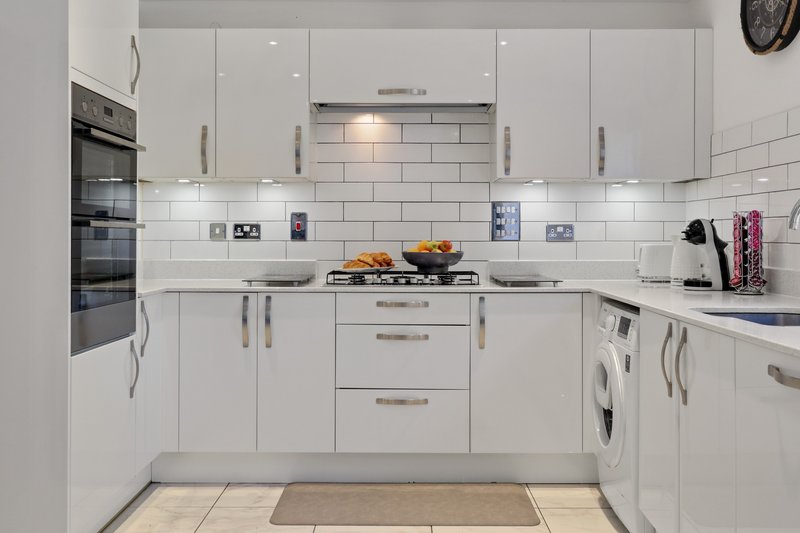 Modern white kitchen with subway tile backsplash, stainless steel appliances and central island