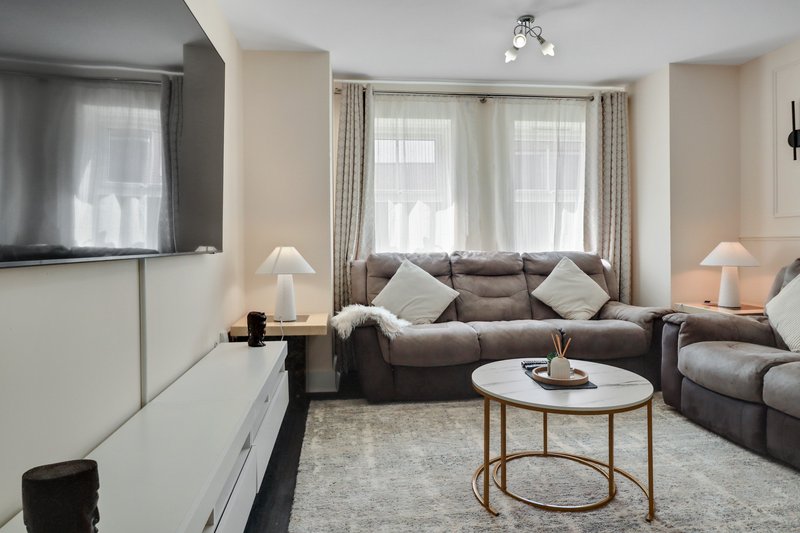 Modern living room with grey sofa, round coffee table, large windows and neutral decor
