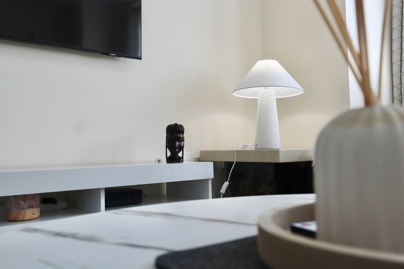 Modern living room with wall-mounted TV, white mushroom lamp, and minimalist shelving