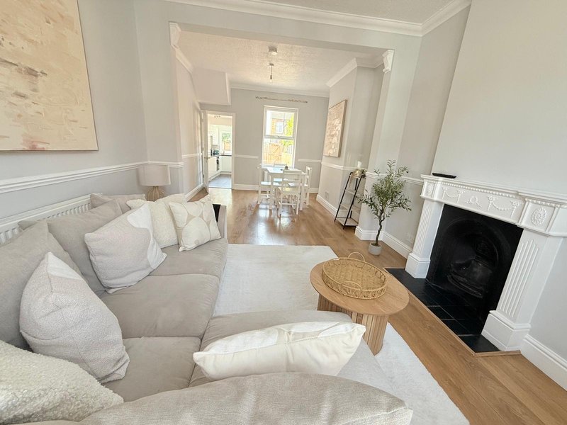 Bright living room with curved sofa, fireplace, wooden floors and hallway leading to rooms