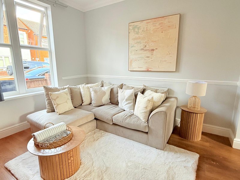 Bright living room with beige corner sofa, cushions, wooden coffee table and cream rug