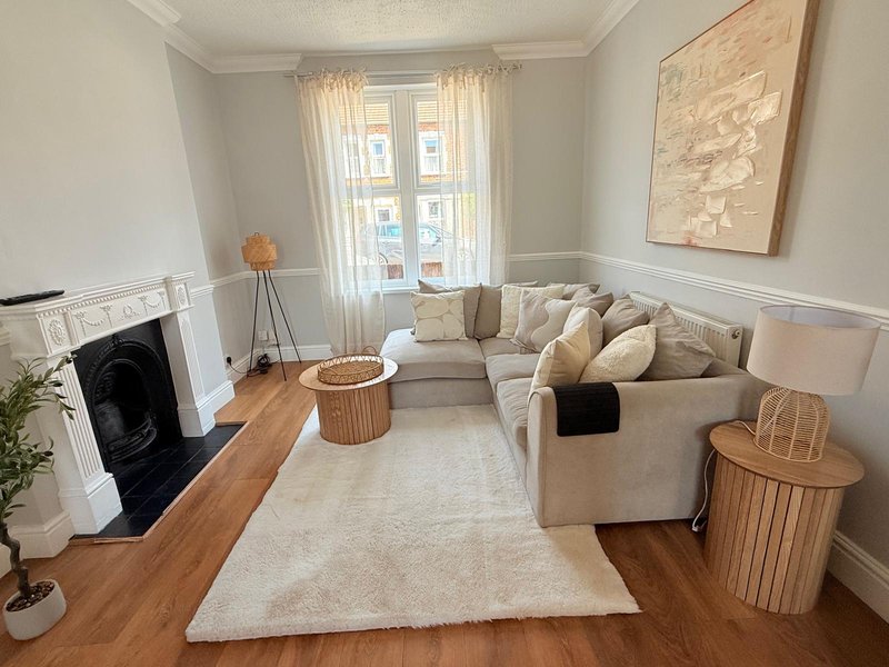 Bright living room with beige corner sofa, fireplace, wooden floor and large windows