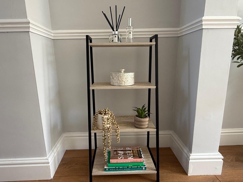 Metal shelving unit with decorative items, plants, books and woven basket in corner