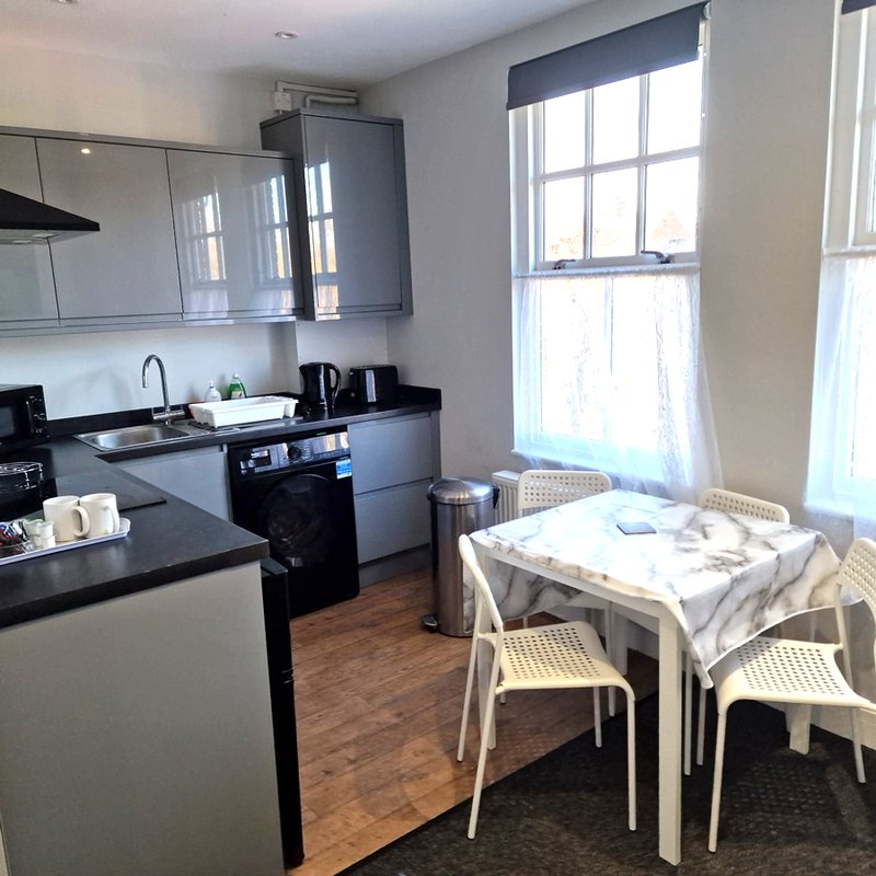 Modern kitchen with black and white cabinetry, dining table with chairs, and large window