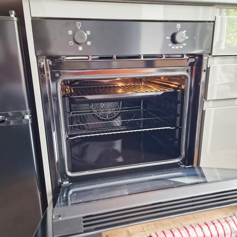 Built-in stainless steel oven with open door showing interior racks and heating element