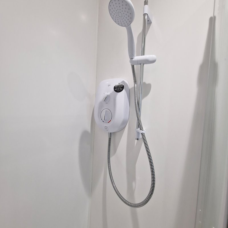 Bathroom shower unit with white electric heater and overhead rainfall showerhead