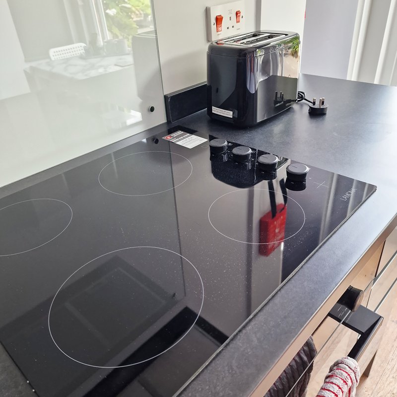 Modern kitchen with black induction cooktop, toaster, and window overlooking garden